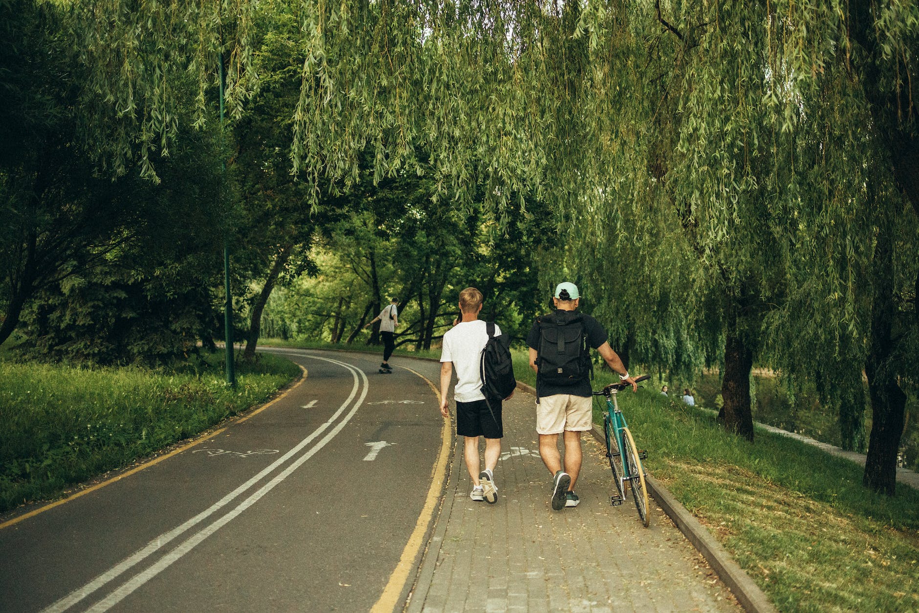 men carrying backpacks walking on sidewalk