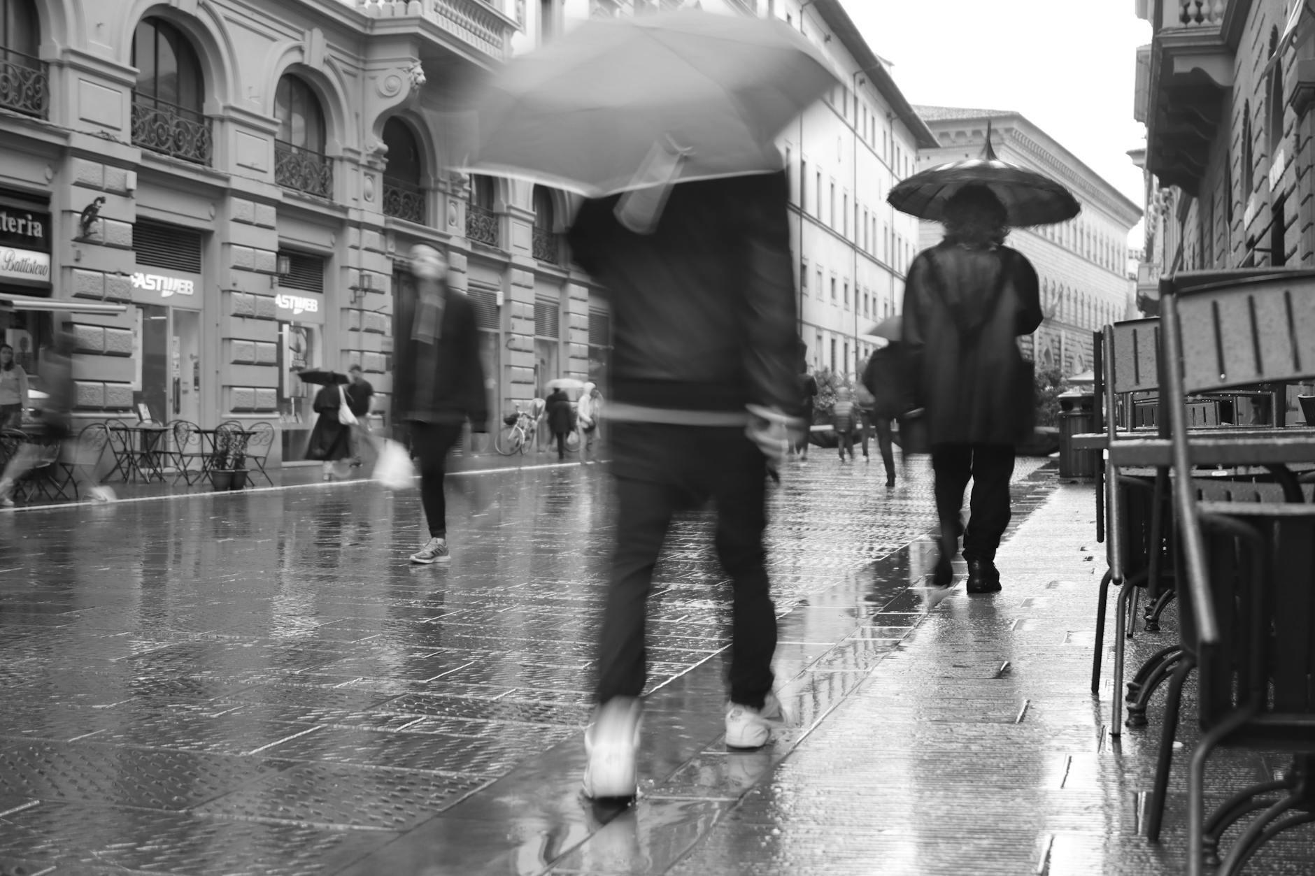 people with umbrellas in florence in black and white