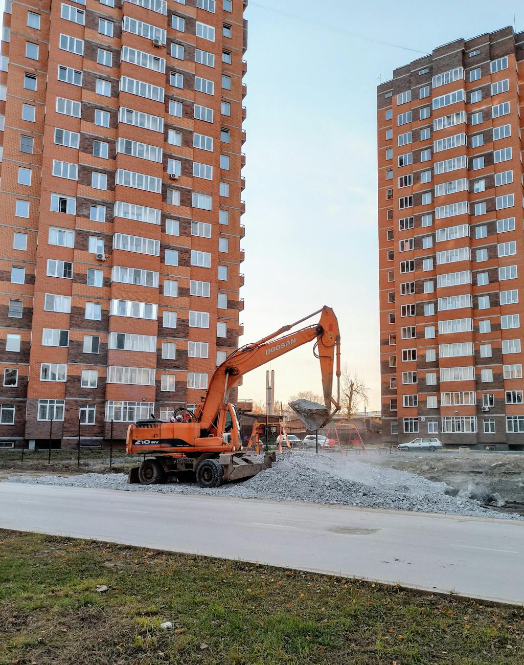 orange and black excavator on road near high rise building